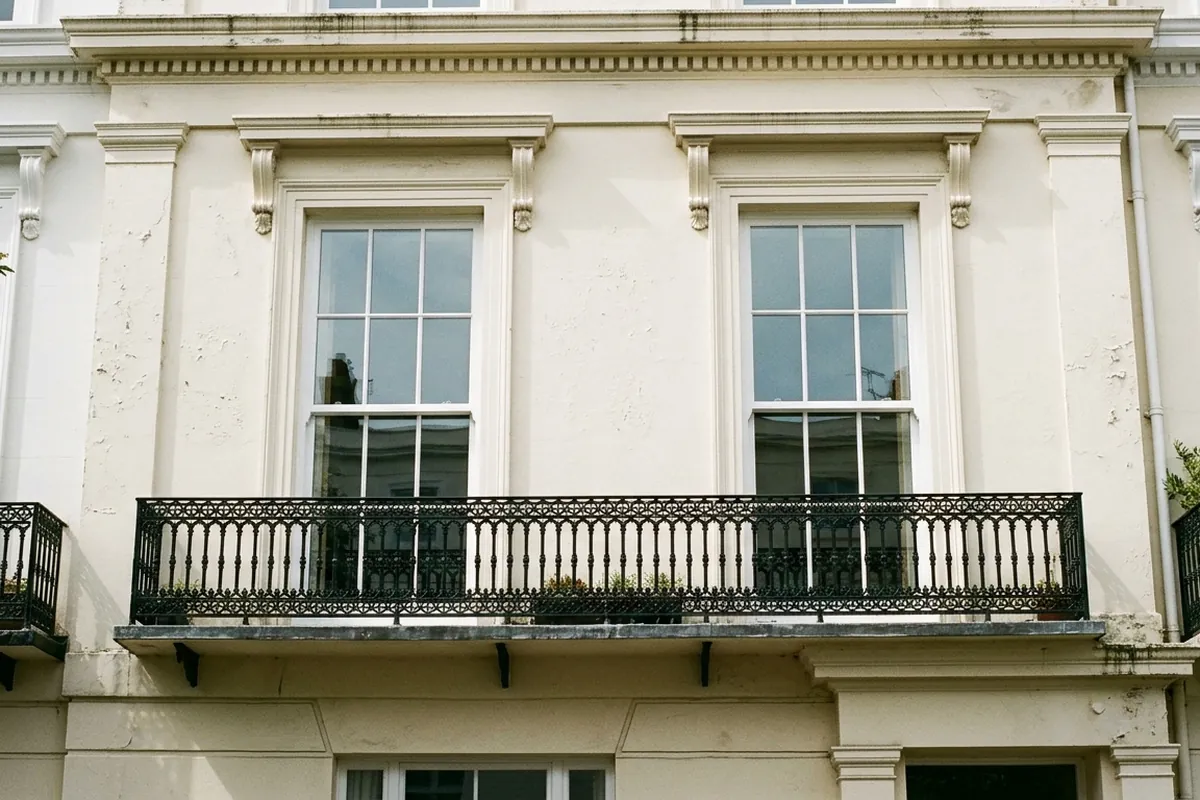 Illustration of two tall six-over-six sash windows above a balcony on a Regency house